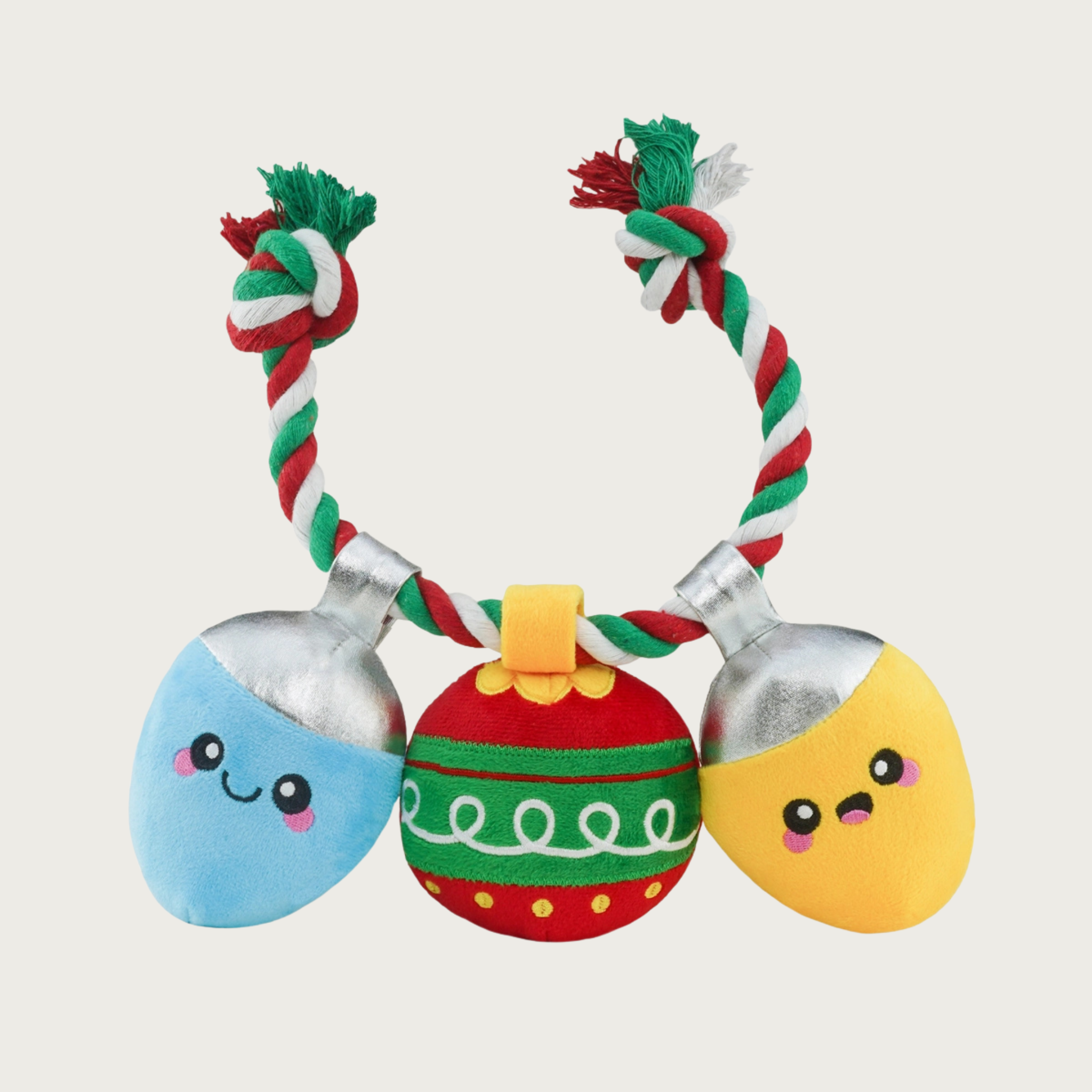 Brightly colored, Christmas-themed rope dog toy, with three plush toys strung along it. The rope is red, white & green. Toys are: light blue holiday light bulb; red, green & gold round ornament, and a yellow holiday light bulb. Both light bulbs have cute, embroidered facial expressions.