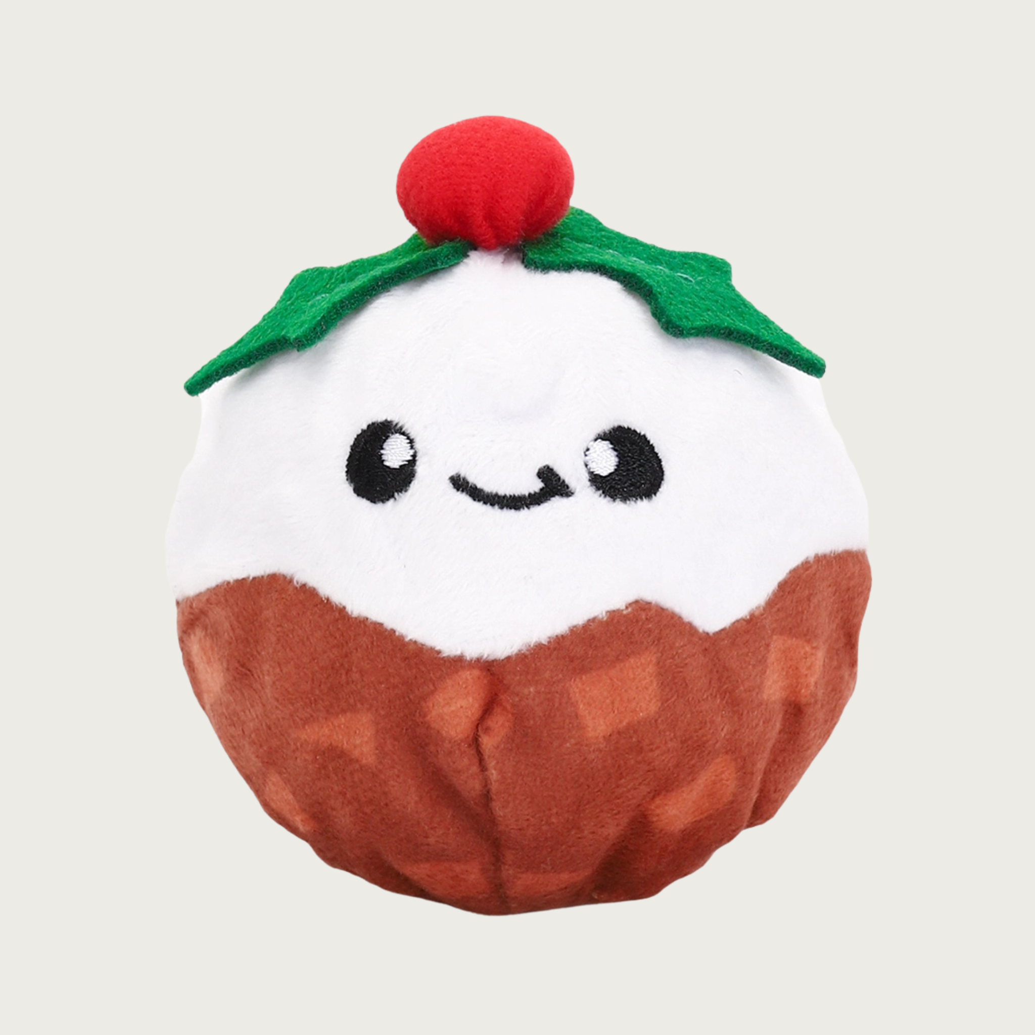 Christmas-themed ball shaped dog toy. Its plush exterior cover is 1/2 brown and 1/2 white, with an embroidered smiley facial expression. It's topped with a felt holly sprig accent.