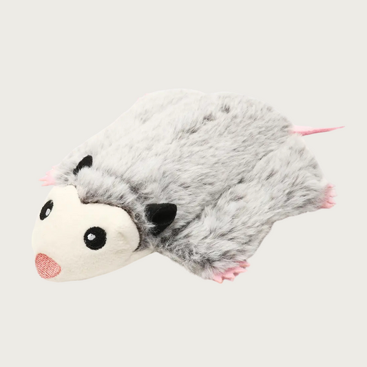 Plush dog toy shaped like an opossum laying flat on its tummy. It has light gray fur, black ears & eyes, and pink nose, feet & tail. Facial features are embroidered.