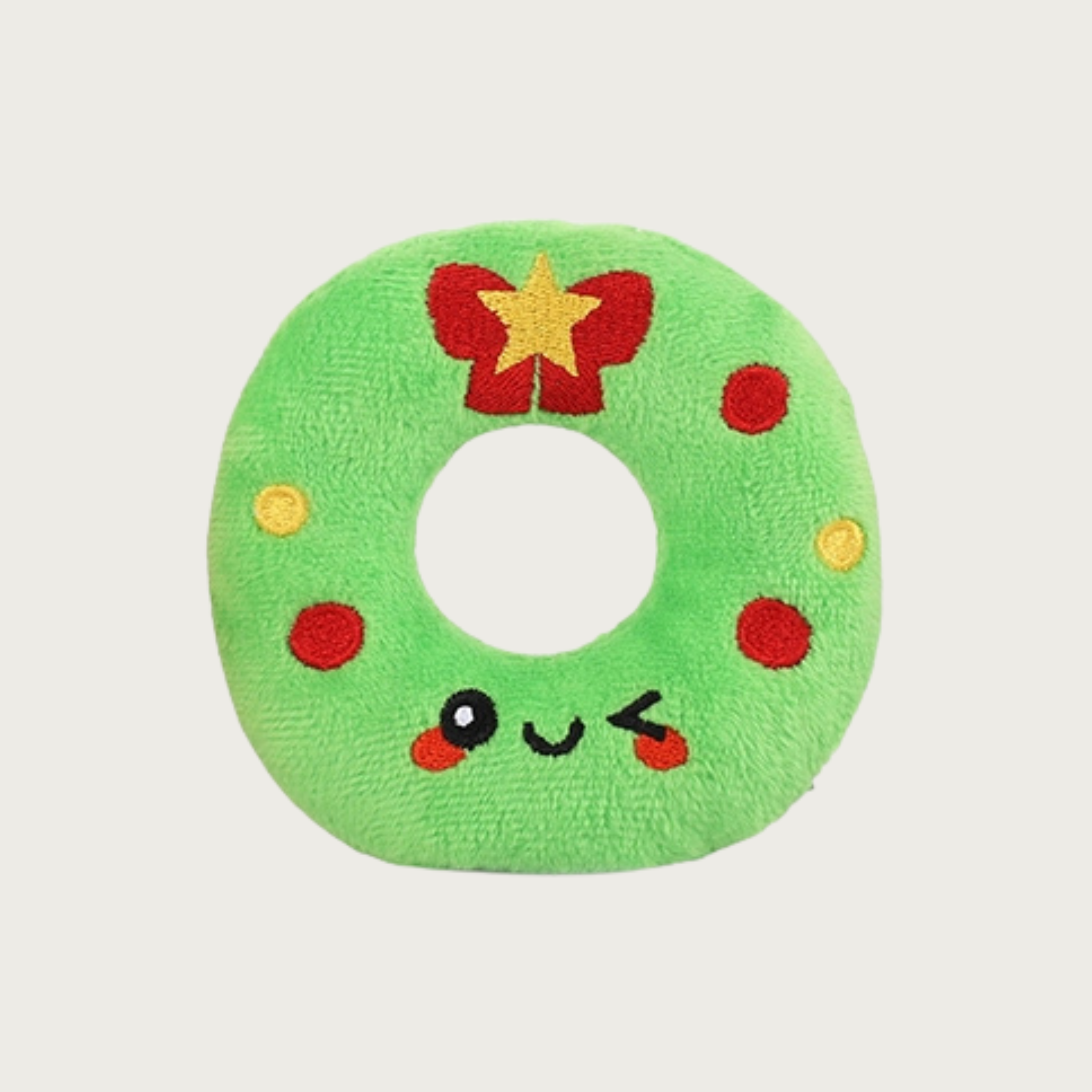 Bright green wreath plush dog toy with embroidered red bow & gold star on top with red & gold "ornaments" and a cute, winking facial expression.