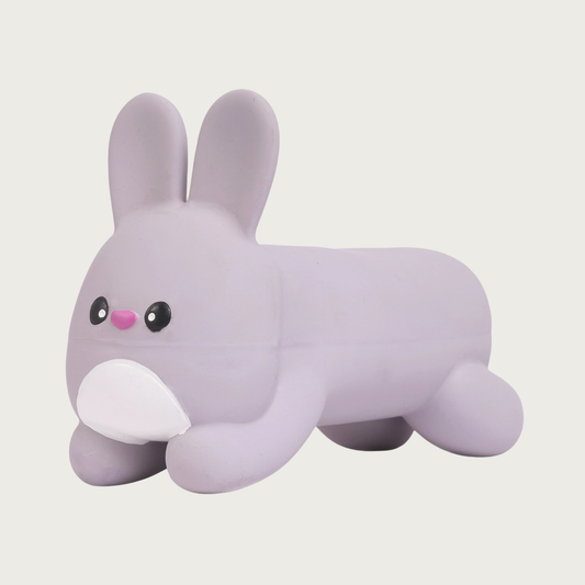 Pale gray latex dog toy shaped like a bunny on its tummy. It has long ears that stand out, and rounded arms & legs. 