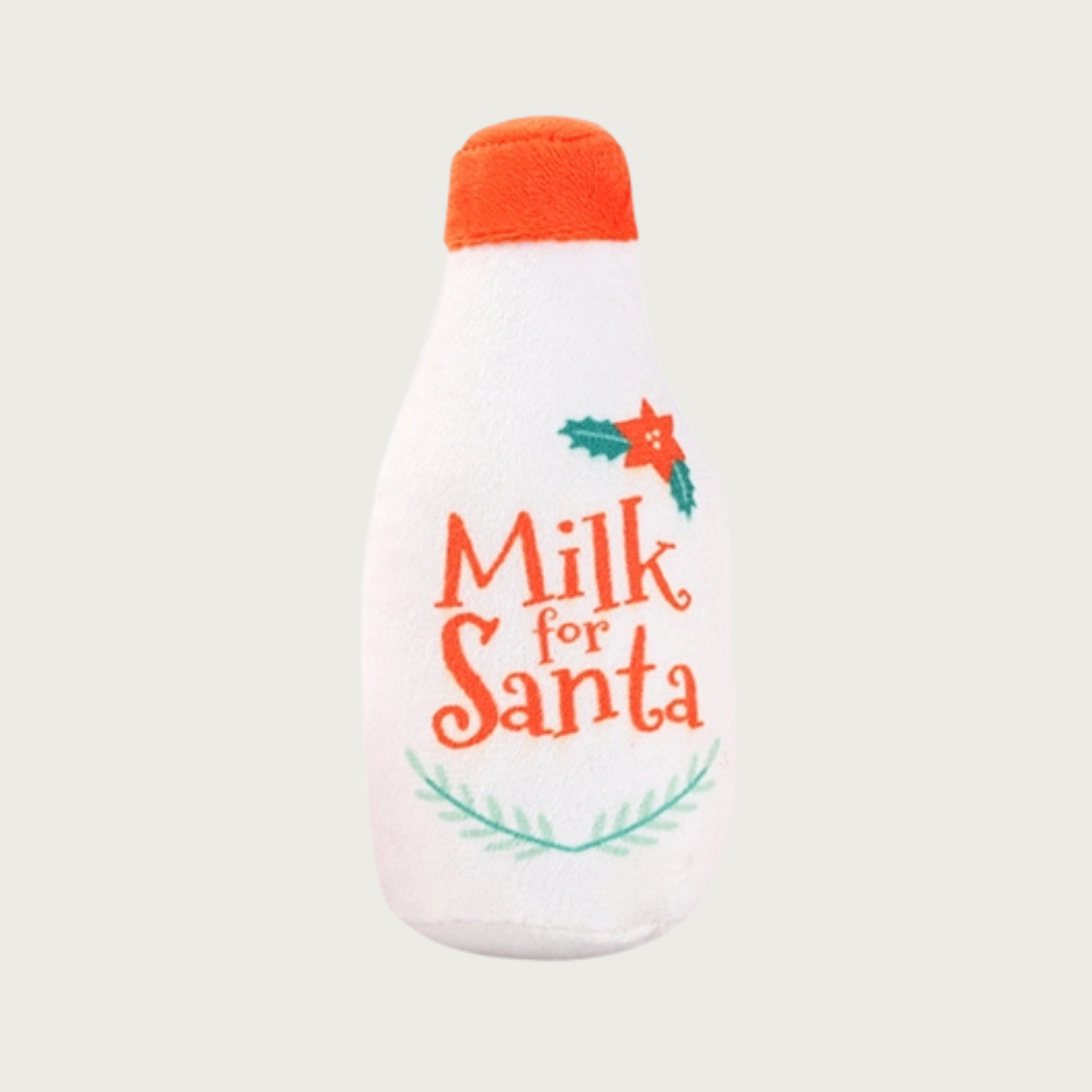 Bottle-shaped plush dog toy labeled 'Milk for Santa' with decorative holly & evergreen accents. It is white with a red "cap".