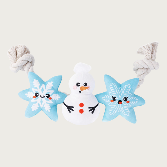 Winter-themed rope dog toy, with three plush toys strung along it. The rope is natural white. Toys are: 2 light blue snowflakes with white details; and a snowman with classic details. All toys have cute, embroidered facial expressions.