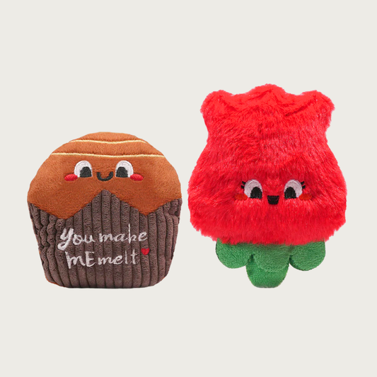 Two plush, Valentine's Day themed dog toys. One looks like a chocolate candy in a wrapper, the other a red rose.