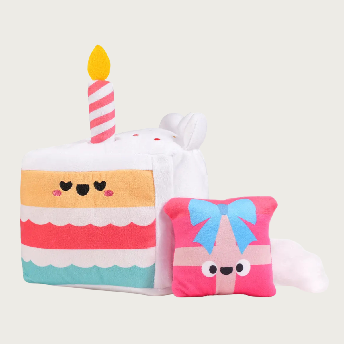 Additional view of the cake slice dog toy, with the small, plush gift box that will be found inside, once the dog tears the cake open. The gift box is pink with pink & blue ribbon and a smiley face.