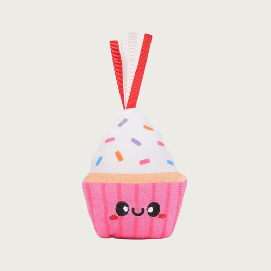 Cupcake shaped plush cat toy. It has a bright pink base with a smiling face and white "frosting" with sprinkles. There are short, red & white ribbons coming out of the top. 