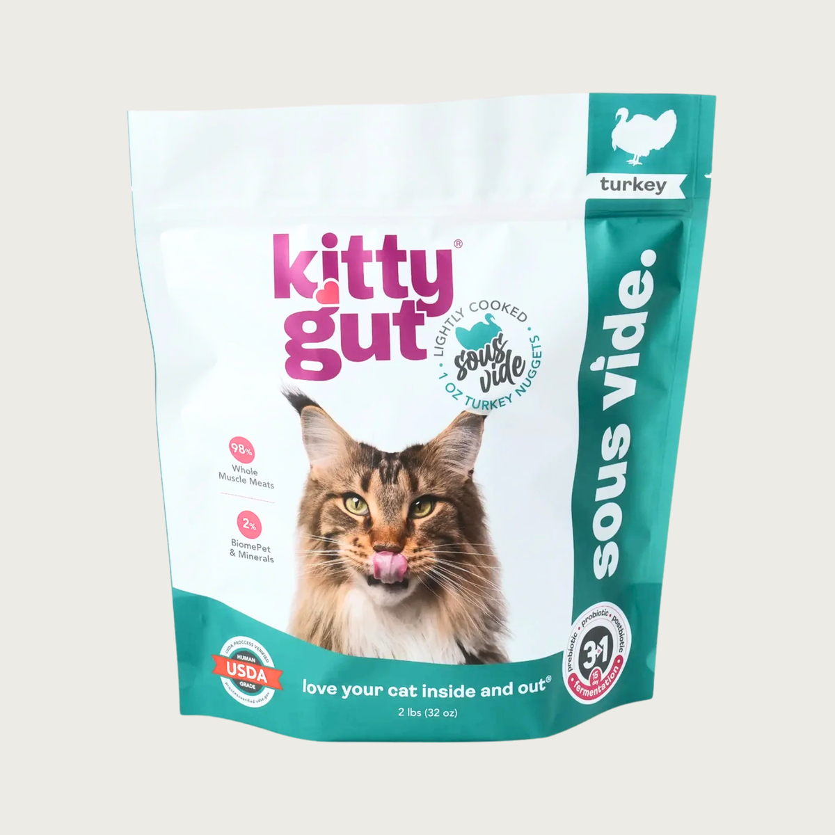 A 2 lb bag of Kitty Gut sous vide lightly cooked turkey cat food, featuring a white and teal stand-up, resealable bag with a picture of a Maine Coon cat on the front. 1 oz nuggets.