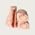 Load image into Gallery viewer, Three raw beef marrow bones with visible meat on them; two are on their sides, showing the marrow in their centers.
