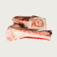 Load image into Gallery viewer, Two raw beef marrow bones with visible meat on them; one is on its side, showing the marrow in its center.
