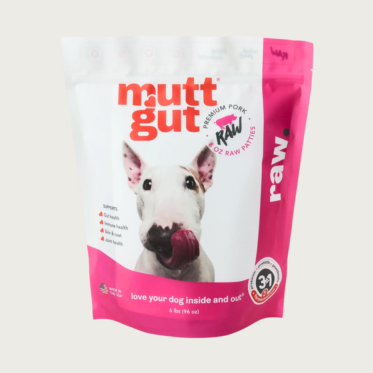 A 6 lb bag of Mutt Gut raw pork dog food, featuring a white and hot pink stand-up, resealable bag with a picture of a Bull Terrier on the front. Text called out in red circles on the left side of the bag reads: 90% whole muscle meats 8% organic vegetables, 2% BiomePet & Minerals. 6 lbs.