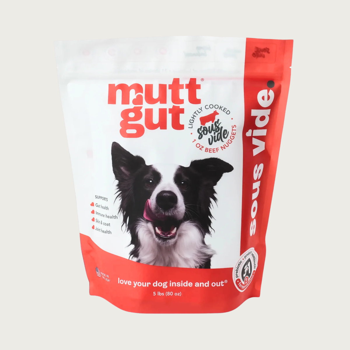 A 5 lb bag of Mutt Gut sous vide lightly cooked beef dog food, featuring a white and red stand-up, resealable bag with a picture of a Border Collie on the front. 1 oz nuggets.