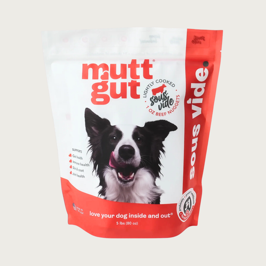 A 5 lb bag of Mutt Gut sous vide lightly cooked beef dog food, featuring a white and red stand-up, resealable bag with a picture of a Border Collie on the front. 1 oz nuggets.
