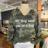 A camouflage hoodie in shades of olive green, with a slight v-neck. White text on chest reads "My dog said you're a hoe."