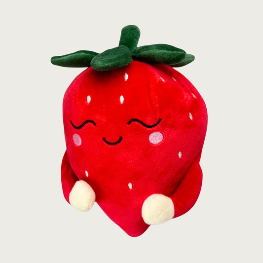 Plush red strawberry dog toy with a sweet embroidered smiling face, green leaves on its head, and small arms forming a hug.