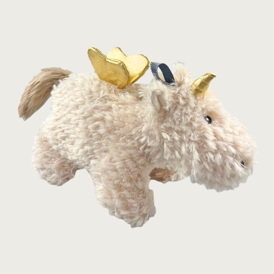 Cream-colored, softly textured plush dog toy. It has a cow's body & face, with a golden unicorn horn and gold wings.