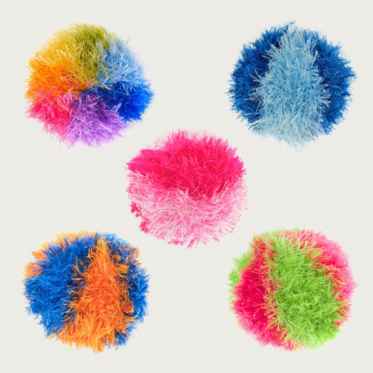 A group of five, different colored OoMaLoo Ball dog toys. They are covered in longer fabric strands (about 1" long) that look fuzzy, like hair. The color options are: rainbow, light blue/dark blue, pink/hot pink, blue/orange, and green/hot pink.