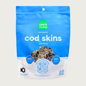A 2.2.5 oz blue & white bag of Open Farm Dehydrated Cod Skins Dog Treats. Small photo in center shows a close-up of a few of the square shaped treats.