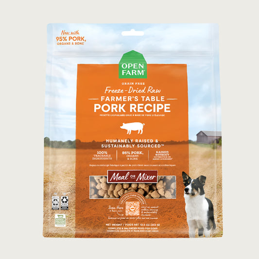A 13.5 oz bag of Grain Free, Open Farm Freeze-Dried-Raw Farmer's Table Pork Recipe dog food. Meal or Mixer, Humanely raised and sustainably sourced. A photo of a Border Collie dog standing in a field on a farm covers the bag, with an orange bar in the center to highlight the white text over it.