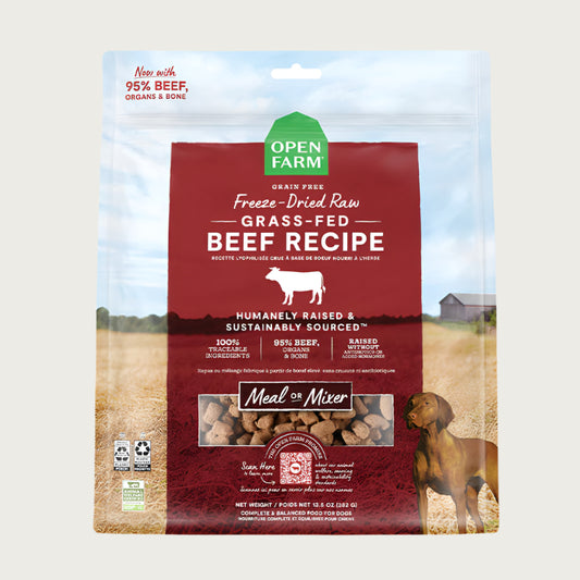 A 13.5 oz bag of Grain Free, Open Farm Freeze-Dried-Raw Grass-Fed Beef Recipe dog food. Meal or Mixer, Humanely raised and sustainably sourced. A photo of a Vizsla dog standing in a field on a farm covers the bag, with a red bar in the center to highlight the white text over it.