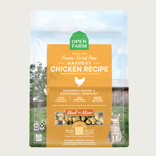 A 9 oz bag of Grain Free, Open Farm Freeze-Dried-Raw Harvest Chicken Recipe cat food. Meal or Mixer, Humanely raised and sustainably sourced. A photo of a tabby cat standing in a field on a farm covers the bag, with a yellow bar in the center to highlight the white text over it.