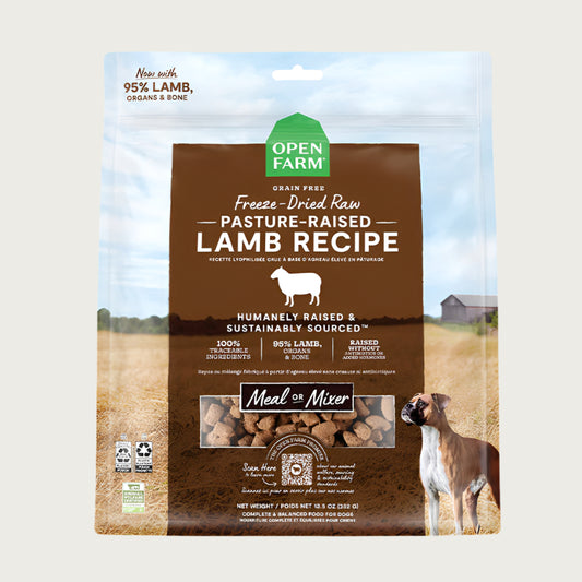 A 13.5 oz bag of Grain Free, Open Farm Freeze-Dried-Raw Pasture-Raised Lamb Recipe dog food. Meal or Mixer, Humanely raised and sustainably sourced. A photo of a Boxer dog standing in a field on a farm covers the bag, with a brown bar in the center to highlight the white text over it.