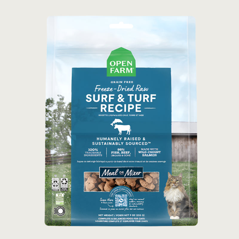 A 9 oz bag of Grain Free, Open Farm Freeze-Dried-Raw Surf & Turf Recipe cat food. Meal or Mixer, Humanely raised and sustainably sourced. A photo of a Maine Coon cat standing in a field on a farm covers the bag, with a blue bar in the center to highlight the white text over it.