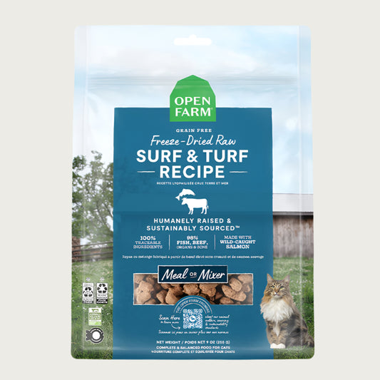 A 9 oz bag of Grain Free, Open Farm Freeze-Dried-Raw Surf & Turf Recipe cat food. Meal or Mixer, Humanely raised and sustainably sourced. A photo of a Maine Coon cat standing in a field on a farm covers the bag, with a blue bar in the center to highlight the white text over it.