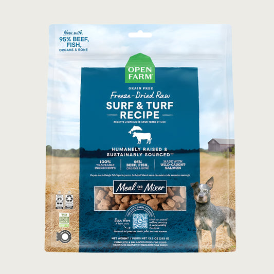 A 13.5 oz bag of Grain Free, Open Farm Freeze-Dried-Raw Surf & Turf Recipe dog food. Meal or Mixer, Humanely raised and sustainably sourced. A photo of a Cattle Dog standing in a field on a farm covers the bag, with a blue bar in the center to highlight the white text over it.