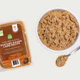 A close-up bowl of Open Farm's Gently Cooked Lamb recipe, showing a tan colored, well blended & smooth food, with small bits of orange (carrots) visible.