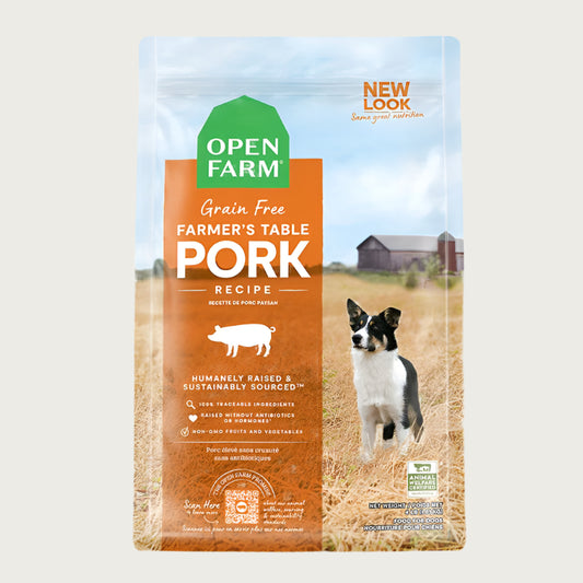 A bag of Open Farm Grain Free Pork Recipe dog food. Humanely raised and sustainably sourced. A photo of a Border Collie dog standing in a field on a farm covers the bag, with an orange bar behind the white text to highlight it.