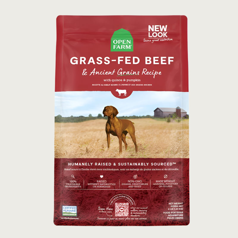 A bag of Open Farm Beef & Ancient Grains Recipe dog food. Humanely raised and sustainably sourced. A photo of a Vizsla dog standing in a field on a farm is in the center 1/3 of the bag, with a red band on the top 1/3 and bottom 1/3 behind white text to highlight it.