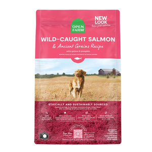 A bag of Open Farm Salmon & Ancient Grains Recipe dog food. Humanely raised and sustainably sourced. A photo of a Retriever dog standing in a field on a farm is in the center 1/3 of the bag, with a pink band on the top 1/3 and bottom 1/3 behind white text to highlight it.