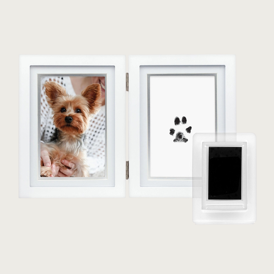 Foldable white photo frame, with a photo of a dog on the left and a black paw print impression on solid white card on the right. Inner mat is pale gray/silver. Sample black ink pad is also pictured.