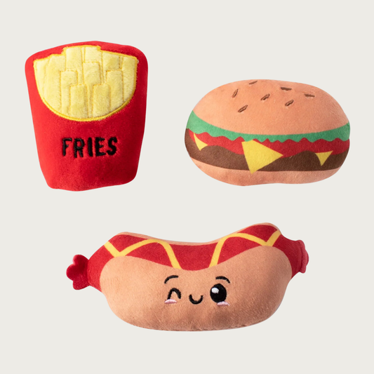 Three small, plush dog toys shaped like a hot dog, hamburger, and fries.