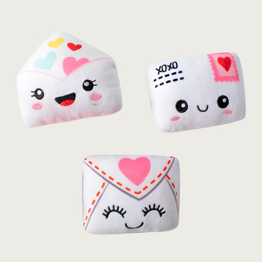 Three Valentine's Day themed plush dog toys shaped like envelopes, with sweet embroidered facial expressions and heart accents.