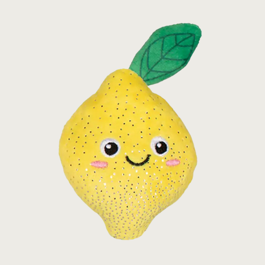 Yellow plush whole lemon shaped dog toy, with a green leaf on top, with embroidered smiley face details. Body has tiny silvery dot accents.