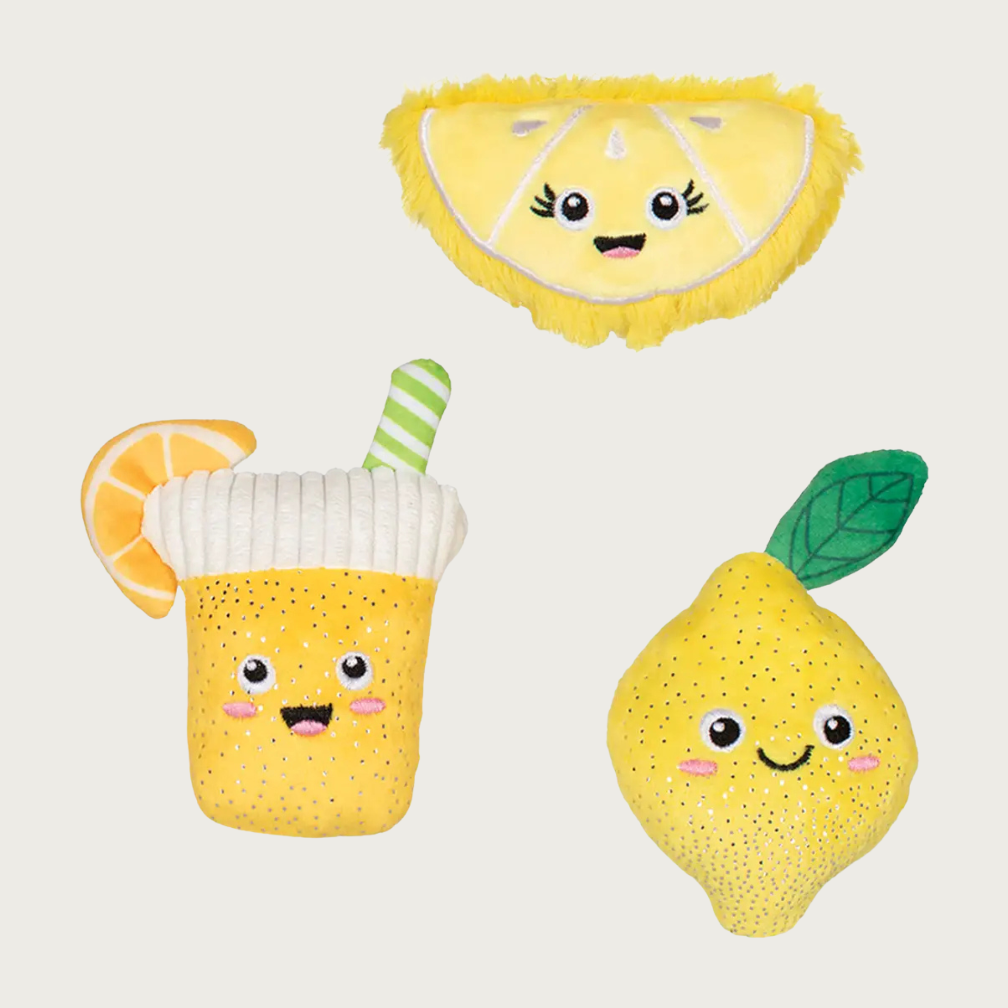 Three plush dog toys with a lemon theme, all with embroidered cute smiley faces. There is a yellow lemon wedge slice, a yellow whole lemon with a green leaf, and a yellow glass of lemonade with a green & white striped straw and lemon slice accent.