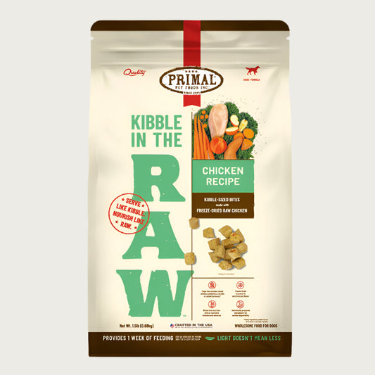 A 1.5 pound bag of chicken recipe Kibble in the Raw dog food from Primal Pet Foods. Text on bag reads "Kibble sized bites made with freeze-dried raw chicken" and "Serve like kibble. Nourish like raw." There is an image of fresh produce with a raw chicken breast, and a smaller image of the bite-sized morsels that are in the bag.