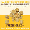 A graphic image with the headline "Light doesn't mean less",  and "DHA to support healthy development". In the center there's a close up image of a handful of the bite-sized pieces. They are tan with orange and green flecks. Underneath the image, the text reads "Freeze-dried = light weight & optimal nutrition".