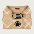 Load image into Gallery viewer, View of Puppia Corwin Step-In vest-style harness for dogs, laid flat. Interior and trim is tan colored, with the exterior cream plaid/check print on tan. Fastener clip on back is black. Accented with black rubber circle behind it, that says Puppia Sports in a repeating circular pattern.
