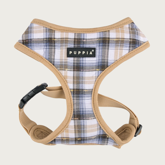 Plaid dog harness with a white base color, with black, navy blue, and tan plaid with tan trim on edges, with a black & white Puppia label in the center of the chest.