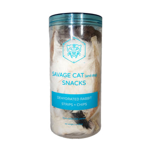 A 3 oz clear plastic container, filled with dehydrated rabbit strips and chips (rabbit hide pieces) by Savage Cat. Fur covered pieces in various natural shades from brown to white are visible.