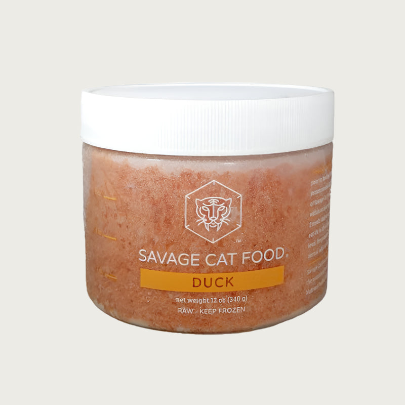 A 12 oz plastic tub of Savage Cat Food, Duck recipe for cats. Tub is clear, with light reddish brown food inside. Raw. Keep Frozen.