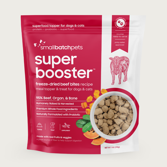 A deep red and white, 7 ounce bag of Smallbatch Super Booster freeze-dried raw beef bites recipe for dogs and cats. Can be used as a meal topper or treat. The bag has a small, clear window showing bite-sized treat pieces, about 1/2" to 1" long.