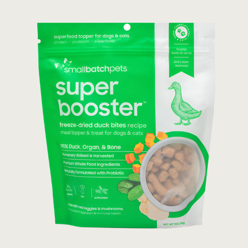 A green and white, 7 ounce bag of Smallbatch Super Booster freeze-dried raw duck bites recipe for dogs and cats. Can be used as a meal topper or treat. The bag has a small, clear window showing bite-sized treat pieces, about 1/2" to 1" long.