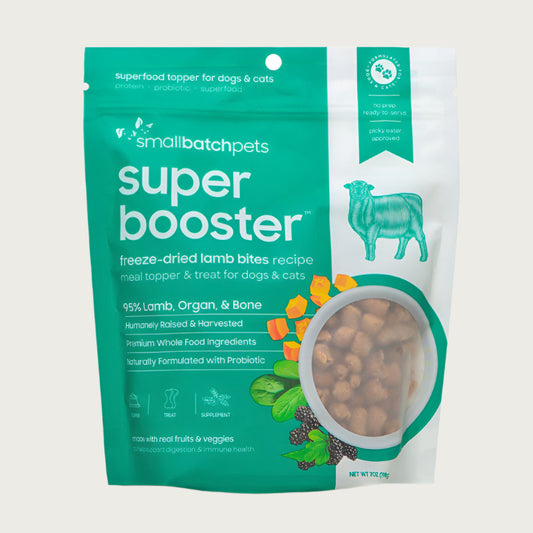 A teal and white, 7 ounce bag of Smallbatch Super Booster freeze-dried raw lamb bites recipe for dogs and cats. Can be used as a meal topper or treat. The bag has a small, clear window showing bite-sized treat pieces, about 1/2" to 1" long.
