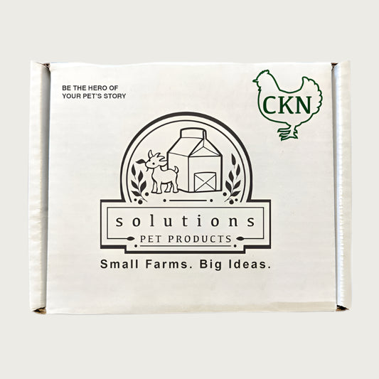 Plain white cardboard box, with text that reads: Be the hero of your pet's story. Center logo says Solutions Pet Products, Small Farms. Big Ideas. Outline of a chicken in the top right corner, with the letters CKN inside it.