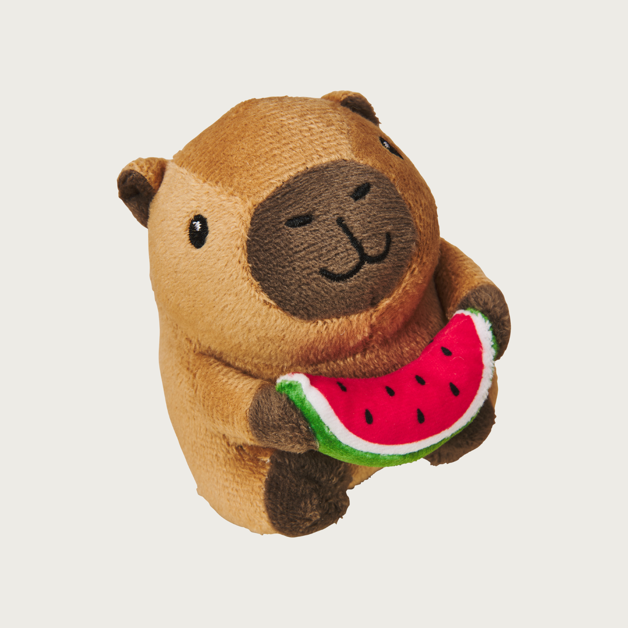 Plush, plump, brown capybara cat toy holding a plush watermelon slice in its hands. Has a cute embroidered facial expression.