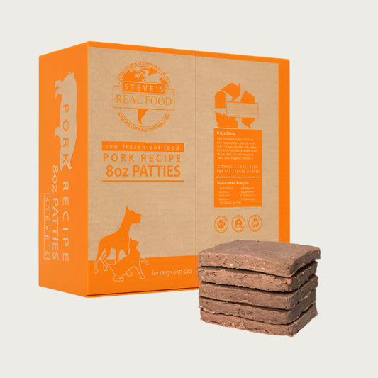 A 14 pound box of Steve's Real Food frozen raw food 8 ounce patties in the pork recipe for both dogs and cats. A plate of the bar shaped patties is positioned in front of the box for reference.