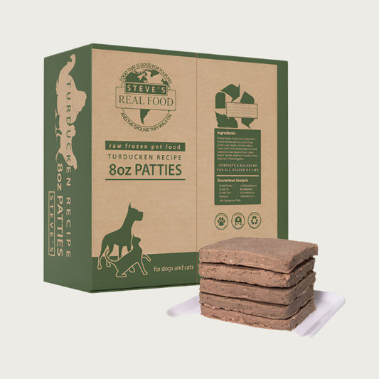 A 14 pound box of Steve's Real Food frozen raw food 8 ounce patties in the turducken (turkey, duck, and chicken) recipe for both dogs and cats. A plate of the bar shaped patties is positioned in front of the box for reference.